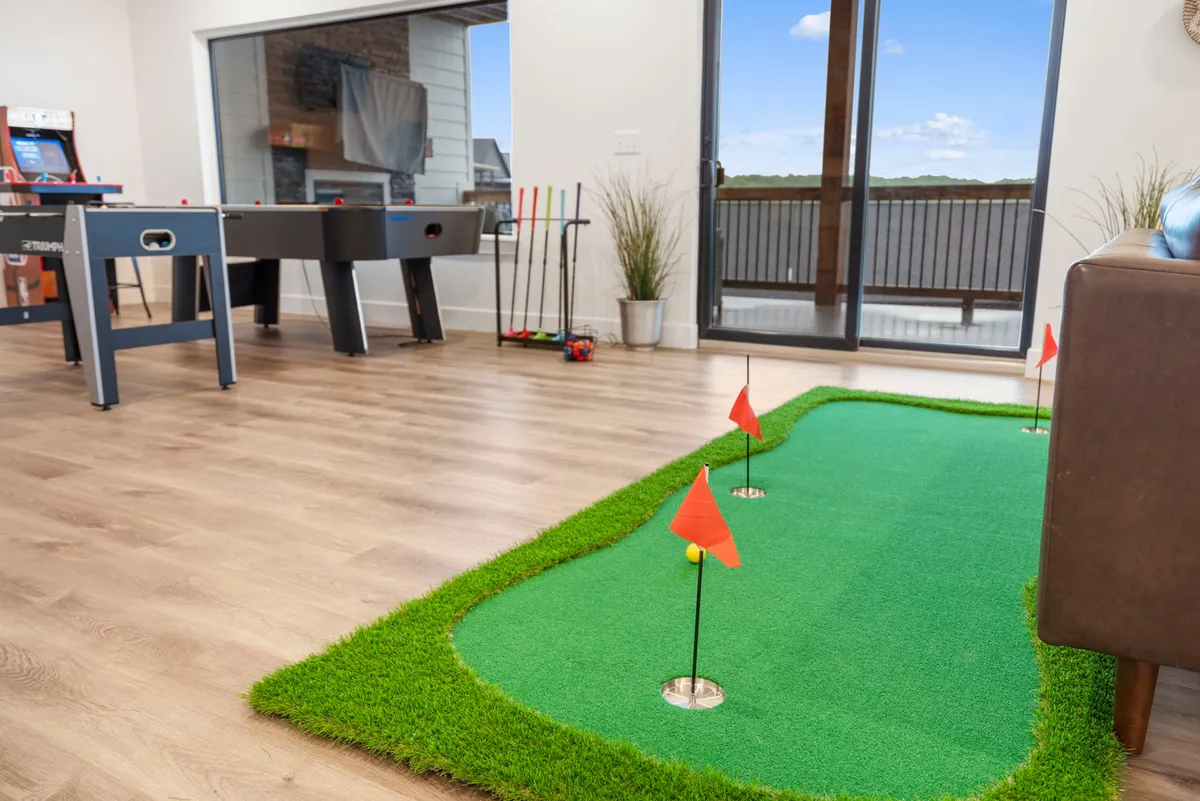 A bright, social area displaying a foosball table, putting green, and large windows with outdoor views. Comfortable seating adds a relaxed vibe, inviting groups to gather for games or casual conversation amidst natural light.