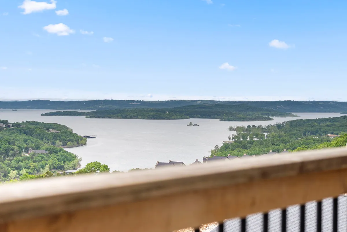 A tranquil view of Table Rock Lake surrounded by lush greenery and distant hills, capturing the essence of lakefront outdoor adventures such as boating, fishing, and hiking. The calm water and expansive landscape evoke a sense of peace and invite exploration.